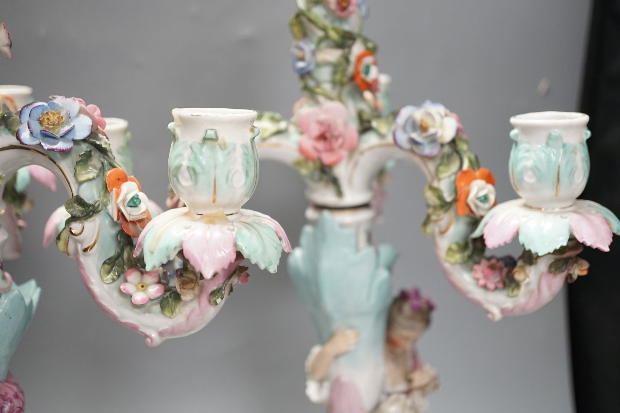 A pair of late 19th century German floral encrusted, figurative porcelain candelabra, 52 cms high.